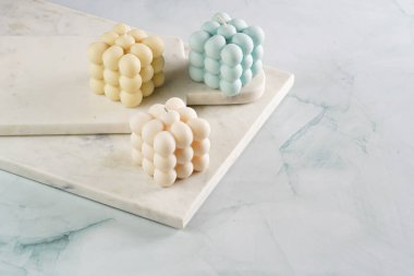 Üç baloncuk mum - soluk mavi yüzey üzerinde bej renkli ve mavi renkli - mermer tahta üzerinde