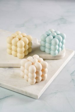 Üç baloncuk mum - soluk mavi yüzey üzerinde bej renkli ve mavi renkli - mermer tahta üzerinde