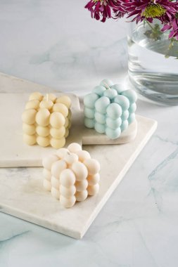 Üç baloncuk mum - soluk mavi yüzey üzerinde bej renkli ve mavi renkli - mermer tahta üzerinde