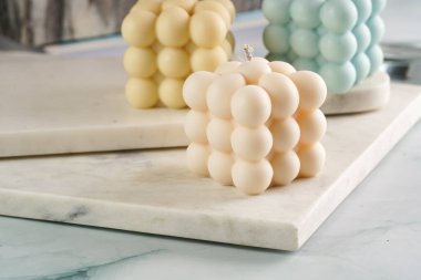 Üç baloncuk mum - soluk mavi yüzey üzerinde bej renkli ve mavi renkli - mermer tahta üzerinde