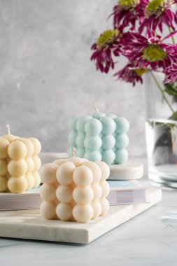 Üç baloncuk mum - soluk mavi yüzey üzerinde bej renkli ve mavi renkli - mermer tahta üzerinde