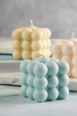 Üç baloncuk mum - soluk mavi yüzey üzerinde bej renkli ve mavi renkli - mermer tahta üzerinde