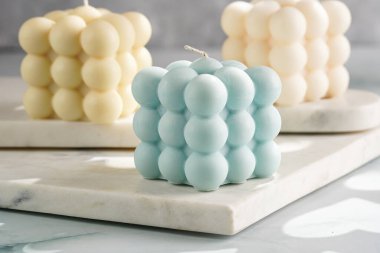 Üç baloncuk mum - soluk mavi yüzey üzerinde bej renkli ve mavi renkli - mermer tahta üzerinde