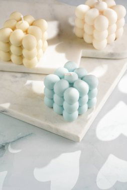 Üç baloncuk mum - soluk mavi yüzey üzerinde bej renkli ve mavi renkli - mermer tahta üzerinde