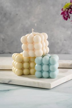 Üç baloncuk mum - soluk mavi yüzey üzerinde bej renkli ve mavi renkli - mermer tahta üzerinde