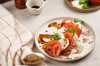 Geleneksel İtalyan salata caprese 'si kırmızı domates, taze fesleğen ve balzamik sirke soslu mozzarella peyniri, ahşap biber ve tuz değirmenlerinden oluşur.