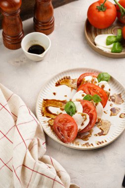 Geleneksel İtalyan salata caprese 'si kırmızı domates, taze fesleğen ve balzamik sirke soslu mozzarella peyniri, ahşap biber ve tuz değirmenlerinden oluşur.