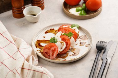 Geleneksel İtalyan salata caprese 'si kırmızı domates, taze fesleğen ve balzamik sirke soslu mozzarella peyniri, ahşap biber ve tuz değirmenlerinden oluşur.