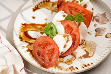 Geleneksel İtalyan salata caprese 'si kırmızı domates, taze fesleğen ve balzamik sirke soslu mozzarella peyniri, ahşap biber ve tuz değirmenlerinden oluşur.