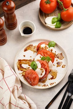 Geleneksel İtalyan salata caprese 'si kırmızı domates, taze fesleğen ve balzamik sirke soslu mozzarella peyniri, ahşap biber ve tuz değirmenlerinden oluşur.