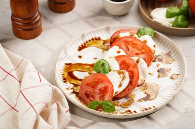 Geleneksel İtalyan salata caprese 'si kırmızı domates, taze fesleğen ve balzamik sirke soslu mozzarella peyniri, ahşap biber ve tuz değirmenlerinden oluşur.