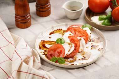 Geleneksel İtalyan salata caprese 'si kırmızı domates, taze fesleğen ve balzamik sirke soslu mozzarella peyniri, ahşap biber ve tuz değirmenlerinden oluşur.