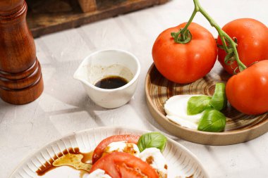 Geleneksel İtalyan salata caprese 'si kırmızı domates, taze fesleğen ve balzamik sirke soslu mozzarella peyniri, ahşap biber ve tuz değirmenlerinden oluşur.
