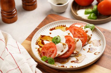 Geleneksel İtalyan salata caprese 'si kırmızı domates, taze fesleğen ve balzamik sirke soslu mozzarella peyniri, ahşap biber ve tuz değirmenlerinden oluşur.