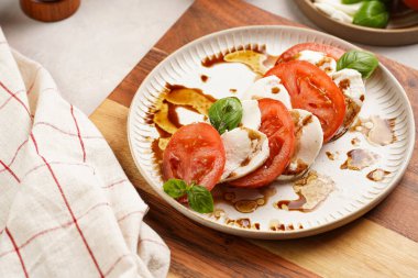 Geleneksel İtalyan salata caprese 'si kırmızı domates, taze fesleğen ve balzamik sirke soslu mozzarella peyniri, ahşap biber ve tuz değirmenlerinden oluşur.
