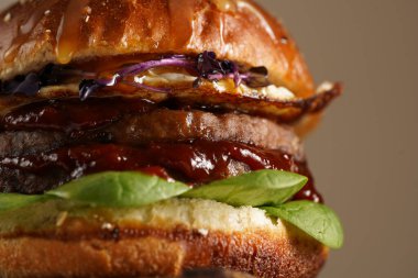 Duble angus bifteği köfteli hamburger, domates, ıspanak, kızarmış yumurta ve barbekü sosu ahşap tahtada, pastel arka planda.