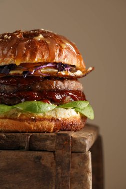 Duble angus bifteği köfteli hamburger, domates, ıspanak, kızarmış yumurta ve barbekü sosu ahşap tahtada, pastel arka planda.