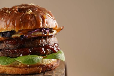 Çift angus biftekli hamburger, domates, ıspanak, sahanda yumurta ve barbekü soslu ahşap tahta, pastel arka plan, kopyalama alanı.