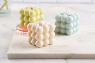 Birçok baloncuk mumu - bej renkli ve mavi renkli - mermer tahtada bahar çiçekli laleler