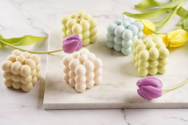 Birçok baloncuk mumu - bej renkli ve mavi renkli - mermer tahtada bahar çiçekli laleler