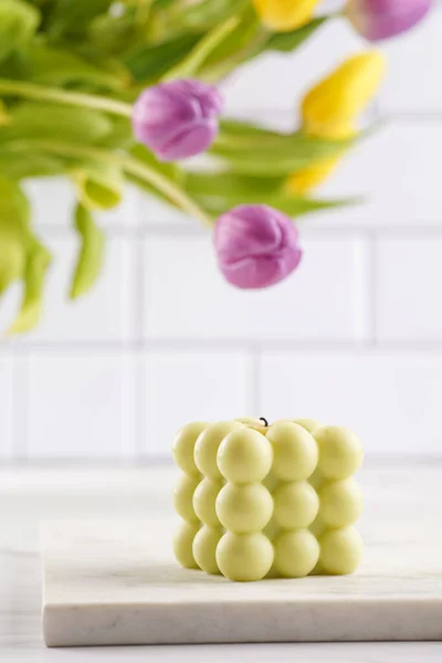 Blassgrüne Blasenkerze Auf Marmorplatte Mit Frühlingsblumen Gelbe Und Lila Tulpen — Stockfoto