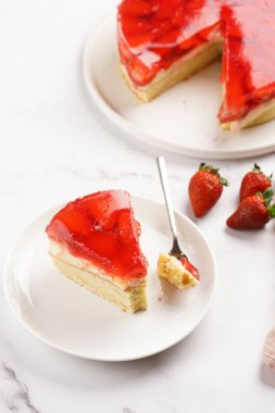 Vanilyalı puding, çilekli jöle ve beyaz mermer arka planda taze çilekli üç katlı bir pasta.