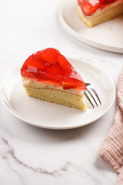 Vanilyalı puding, çilekli jöle ve beyaz mermer arka planda taze çilekli üç katlı bir pasta.