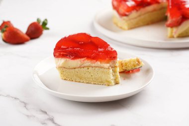 Vanilyalı puding, çilekli jöle ve beyaz mermer arka planda taze çilekli üç katlı bir pasta.