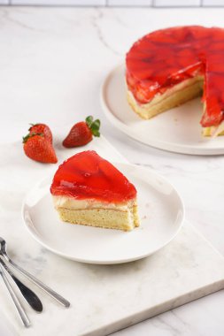 Vanilyalı puding, çilekli jöle ve beyaz mermer arka planda taze çilekli üç katlı bir pasta.