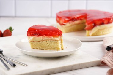 Vanilyalı puding, çilekli jöle ve beyaz mermer arka planda taze çilekli üç katlı bir pasta.