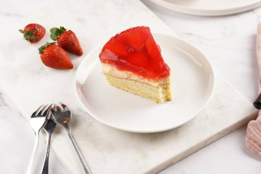 Vanilyalı puding, çilekli jöle ve beyaz mermer arka planda taze çilekli üç katlı bir pasta.