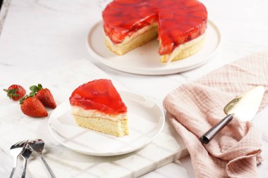 Vanilyalı puding, çilekli jöle ve beyaz mermer arka planda taze çilekli üç katlı bir pasta.