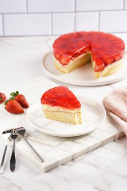 Vanilyalı puding, çilekli jöle ve beyaz mermer arka planda taze çilekli üç katlı bir pasta.