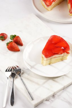 Vanilyalı puding, çilekli jöle ve beyaz mermer arka planda taze çilekli üç katlı bir pasta.