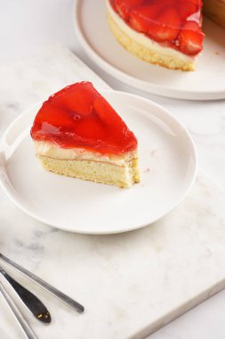 Vanilyalı puding, çilekli jöle ve beyaz mermer arka planda taze çilekli üç katlı bir pasta.