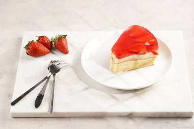 Vanilyalı puding, çilekli jöle ve beyaz mermer arka planda taze çilekli üç katlı bir pasta.