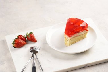 Vanilyalı puding, çilekli jöle ve beyaz mermer arka planda taze çilekli üç katlı bir pasta.