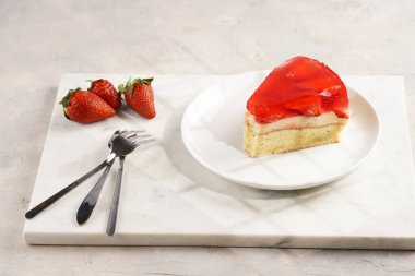 Vanilyalı puding, çilekli jöle ve beyaz mermer arka planda taze çilekli üç katlı bir pasta.