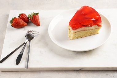 Vanilyalı puding, çilekli jöle ve beyaz mermer arka planda taze çilekli üç katlı bir pasta.