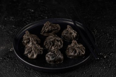 Geleneksel Gürcistan yemeği, khinkali Kalakuri, siyah desenli arka planda kıymalı et ile doldurulmuş siyah hamur tatlısı.