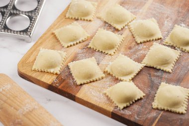 Taze yapılmış geleneksel İtalyan yemeği - ravioli, kıyma ile doldurulmuş hamur tatlısı, tahtadan tahta tahta üzerinde un, alüminyum hazırlık formu.