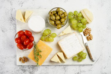 Organik peynirli peynir tabağı - mavi peynirli çedar, emmantaler, güçlü kokulu Fransız yumuşak peyniri, İtalyan parmesan peyniri, üzümler, domates, zeytin, fındık ve mermer tahtada kraker