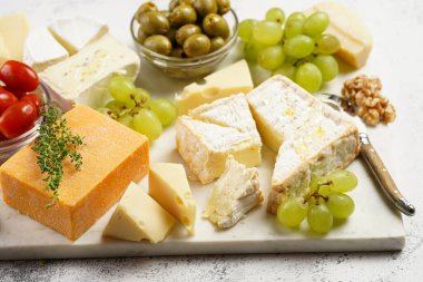 Organik peynirli peynir tabağı - mavi peynirli çedar, emmantaler, güçlü kokulu Fransız yumuşak peyniri, İtalyan parmesan peyniri, üzümler, domates, zeytin, fındık ve mermer tahtada kraker