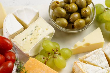 Organik peynirli peynir tabağı - mavi peynirli çedar, emmantaler, güçlü kokulu Fransız yumuşak peyniri, İtalyan parmesan peyniri, üzümler, domates, zeytin, fındık ve mermer tahtada kraker
