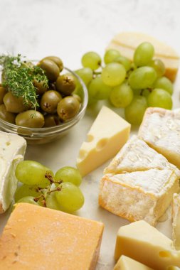Organik peynirli peynir tabağı - mavi peynirli çedar, emmantaler, güçlü kokulu Fransız yumuşak peyniri, İtalyan parmesan peyniri, üzümler, domates, zeytin, fındık ve mermer tahtada kraker
