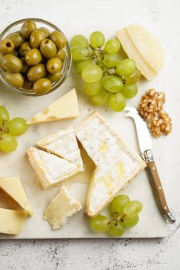 Organik peynirli peynir tabağı - mavi peynirli çedar, emmantaler, güçlü kokulu Fransız yumuşak peyniri, İtalyan parmesan peyniri, üzümler, domates, zeytin, fındık ve mermer tahtada kraker