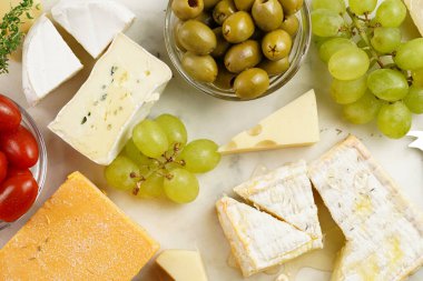 Organik peynirli peynir tabağı - mavi peynirli çedar, emmantaler, güçlü kokulu Fransız yumuşak peyniri, İtalyan parmesan peyniri, üzümler, domates, zeytin, fındık ve mermer tahtada kraker