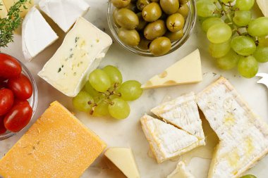 Organik peynirli peynir tabağı - mavi peynirli çedar, emmantaler, güçlü kokulu Fransız yumuşak peyniri, İtalyan parmesan peyniri, üzümler, domates, zeytin, fındık ve mermer tahtada kraker