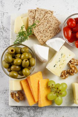 Cheese platter with organic cheeses - blue cheese cheddar, emmantaler, french soft cheese with strong smell, italian parmesan, grapes, tomatoes, olives, nuts and crackers on marble board