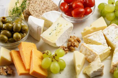 Organik peynirli peynir tabağı - mavi peynirli çedar, emmantaler, güçlü kokulu Fransız yumuşak peyniri, İtalyan parmesan peyniri, üzümler, domates, zeytin, fındık ve mermer tahtada kraker